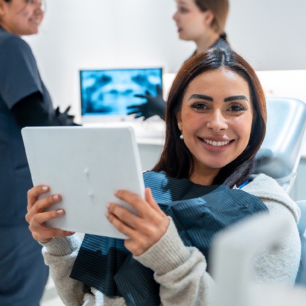 Woman smiling while holding mirror in treatment chair