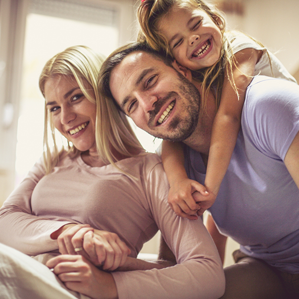 Family of three smiling together at home