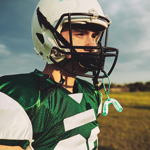 Football player with a mouthguard attached to their helmet