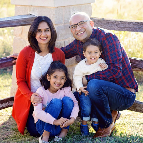 Doctor V smiling in the grass with her husband and two children