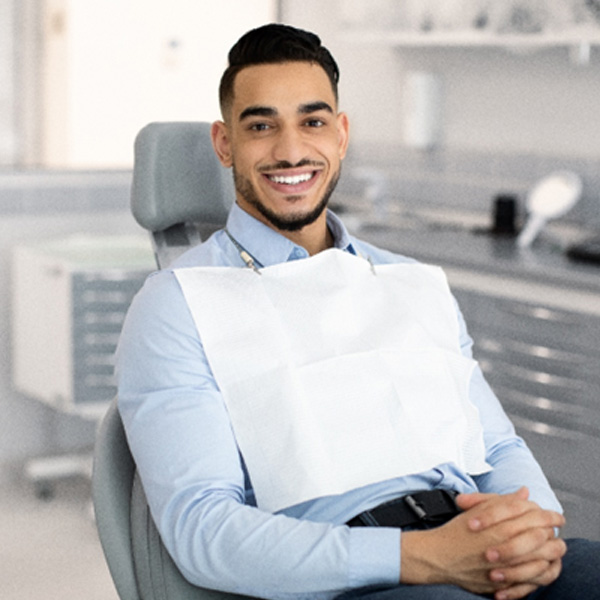 Man sitting in dental chair with hands folded